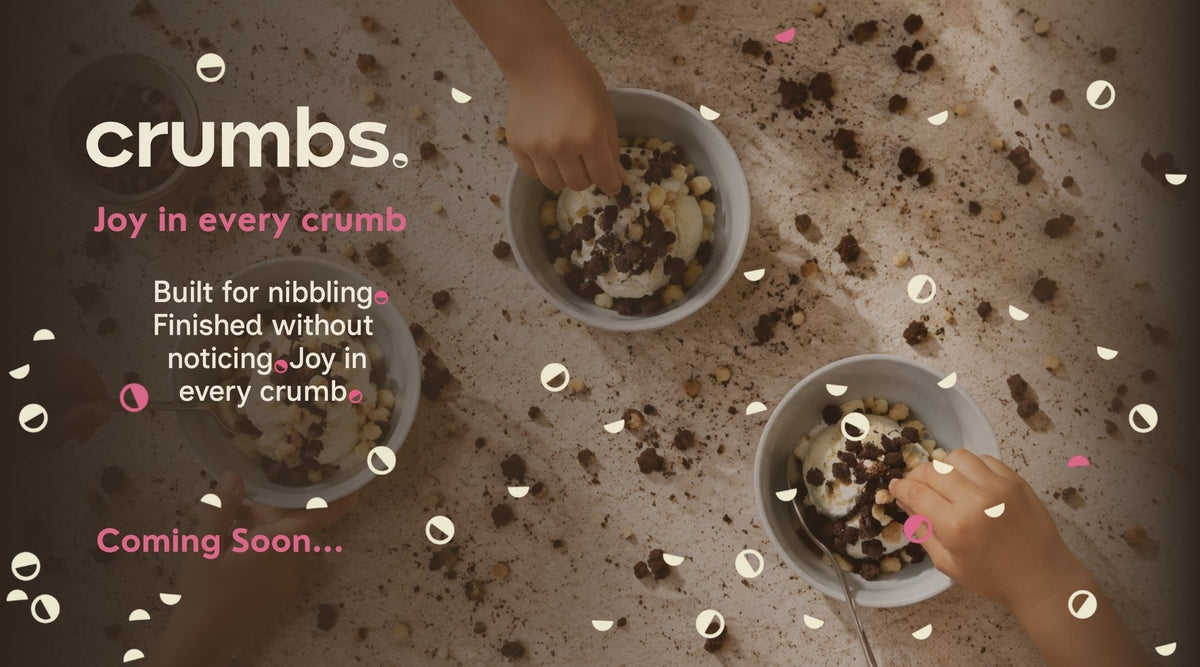 Coming soon promotional graphic for crumbs, showing two bowls of cookie crumb mixture being stirred by hands over a scattered cookie crumb surface, with the text 'crumbs', 'Joy in every crumb', and 'Coming Soon. 